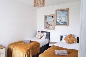 Ein Hotelzimmer mit zwei Betten, einem Nachttisch, einer Lampe und zwei gerahmten Bildern an der Wand.