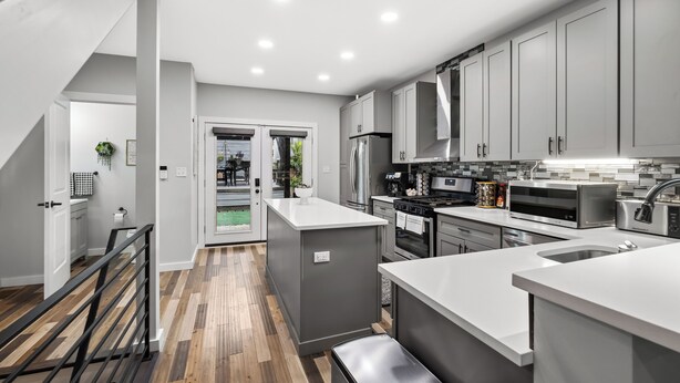 A modern kitchen with grey cabinets, stainless steel appliances, and a wooden floor. - Hot tub, BBQ, Fire pit, Garage, Near Downtown (Pittsburgh)
