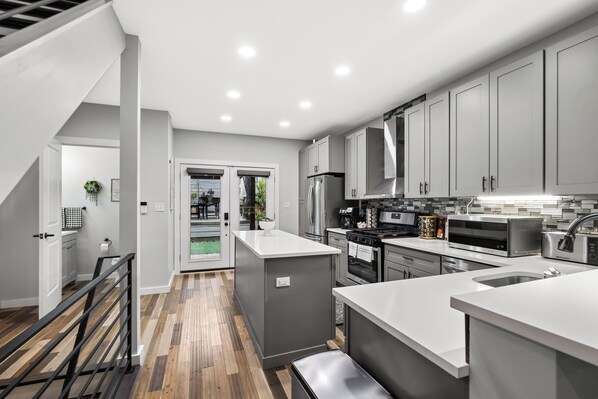 Une cuisine moderne avec des meubles gris, des appareils en acier inoxydable et un plancher en bois.