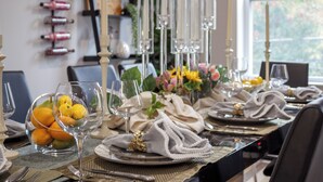A dining table set with plates, cutlery, and a centerpiece of flowers. - Hot tub, BBQ, Fire pit, Garage, Near Downtown (Pittsburgh)