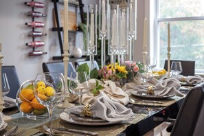 Une table à manger dressée avec des assiettes, des couverts et un centre de table composé de fleurs.