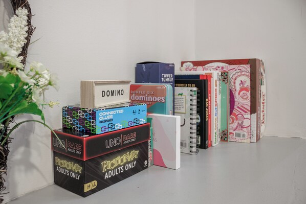 Een verzameling bordspellen en boeken op een plank.
