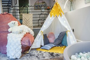 Une pièce confortable avec un lit, un ours en peluche blanc, une tente et une piscine à balles.