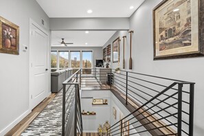 Un intérieur moderne avec un escalier, une vue sur l’extérieur et une bibliothèque.