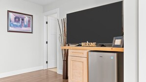 Ein Flur mit Tür, einer Tafel, einem Schild mit der Aufschrift 'Willkommen', einem Kühlschrank und einer Vase mit Ästen.