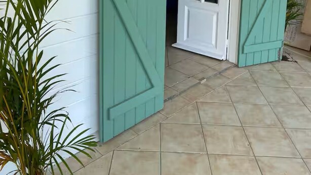 A house with teal shutters, a white door, and a tiled patio. - Kaz'Ary Entire villa in Sainte-Anne, Guadeloupe (Sainte‑Anne)