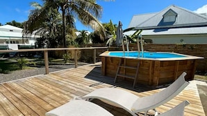 A wooden deck with a pool, lounge chairs, and a palm tree. - Kaz'Ary Entire villa in Sainte-Anne, Guadeloupe (Sainte‑Anne)
