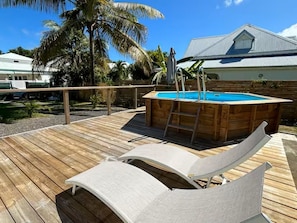 A wooden deck with a pool, lounge chairs, and a palm tree. - Kaz'Ary Entire villa in Sainte-Anne, Guadeloupe (Sainte‑Anne)
