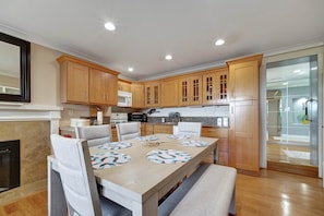 A modern kitchen with wooden cabinets, a dining table with patterned placemats, and a built-in microwave.