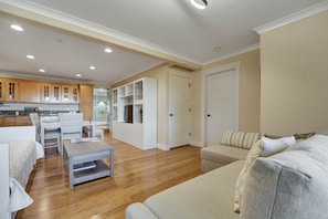 A modern living room with a sofa, a coffee table, and a dining area with chairs and a table.