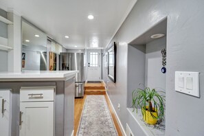 A hallway with a kitchen area, a staircase, and a potted plant.