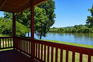 A covered outdoor area with a view of a river and trees.