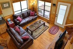 A cozy living room with leather sofas, a coffee table, and a TV.