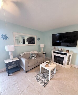 A living room with a sofa, coffee table, TV, fireplace, and decorative items. - Wonderful 2-bedroom condo with AC and 2 pools in Myrtle Beach (Myrtle Beach)