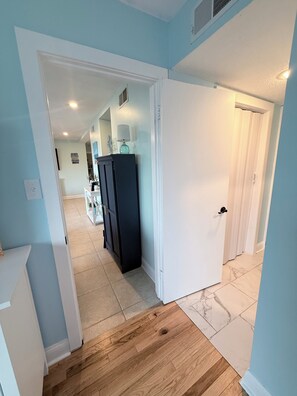 A hallway with a wooden floor, a white door, and a dark-colored refrigerator. - Wonderful 2-bedroom condo with AC and 2 pools in Myrtle Beach (Myrtle Beach)