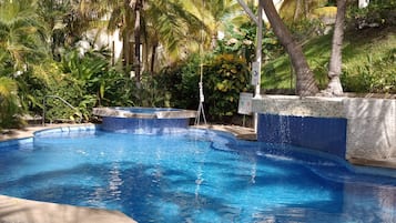 Una piscina rodeada de exuberante vegetación y un edificio al fondo.