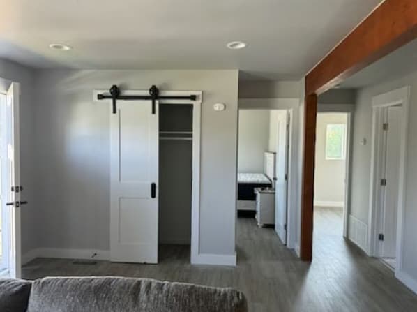 A hallway with a sliding door, a bed, and a door leading to another room.