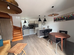 A modern kitchen with a central island, black bar stools, and pendant lighting. - Nice little house 5mn walk from the beach (Ploemeur)