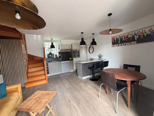A modern kitchen with a central island, black bar stools, and pendant lighting.