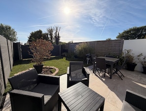 An outdoor patio with wicker furniture, a barbecue grill, and a small garden area.