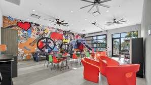 Un interno moderno con sedie colorate, un murale e ventilatori a soffitto.