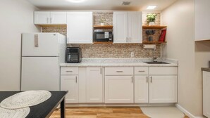 A modern kitchen with white cabinets, a granite countertop, a built-in microwave, and a coffee maker.