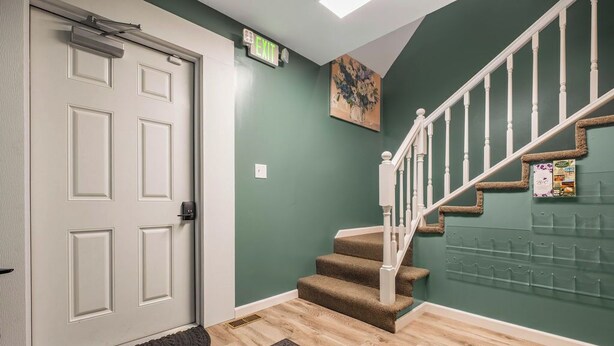 A staircase with carpeted steps, a white door, and a wall-mounted bulletin board.