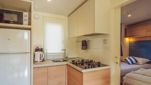 A compact kitchenette with a stove, sink, and a small refrigerator. - Relaxing Premium Family Lounge (Brtonigla)