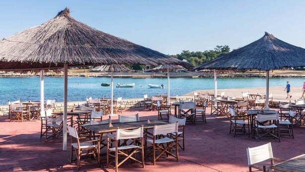 A beachside restaurant with outdoor seating, thatched umbrellas, and a view of the sea. - Relaxing Premium Family Lounge (Brtonigla)