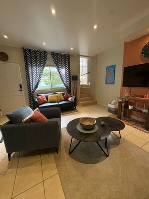 Ein Wohnzimmer mit einer Couch, einem Couchtisch, einem Fernseher und einer Treppe.