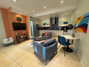 Ein modernes Wohnzimmer mit Flachbildfernseher, Sofa und Essbereich.