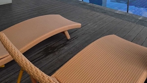 Zona de piscina en la azotea con dos sillones de mimbre, piscina con borde azul y cielo despejado.