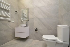 Une salle de bain moderne avec un meuble-lavabo blanc, un miroir, des toilettes et un porte-serviettes.