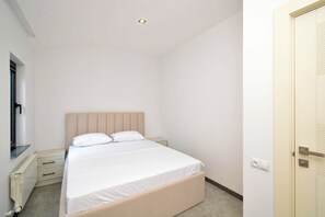 Quarto com cama, janela, radiador, porta e interruptor de luz.