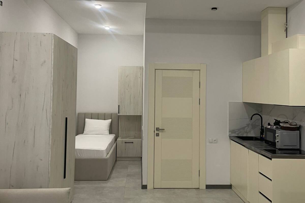 A modern, compact living space with a kitchenette, a bed, and a seating area.