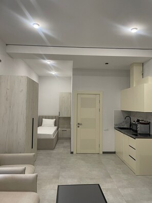 Un espace de vie moderne et compact, comprenant un coin cuisine, un lit et un espace détente.