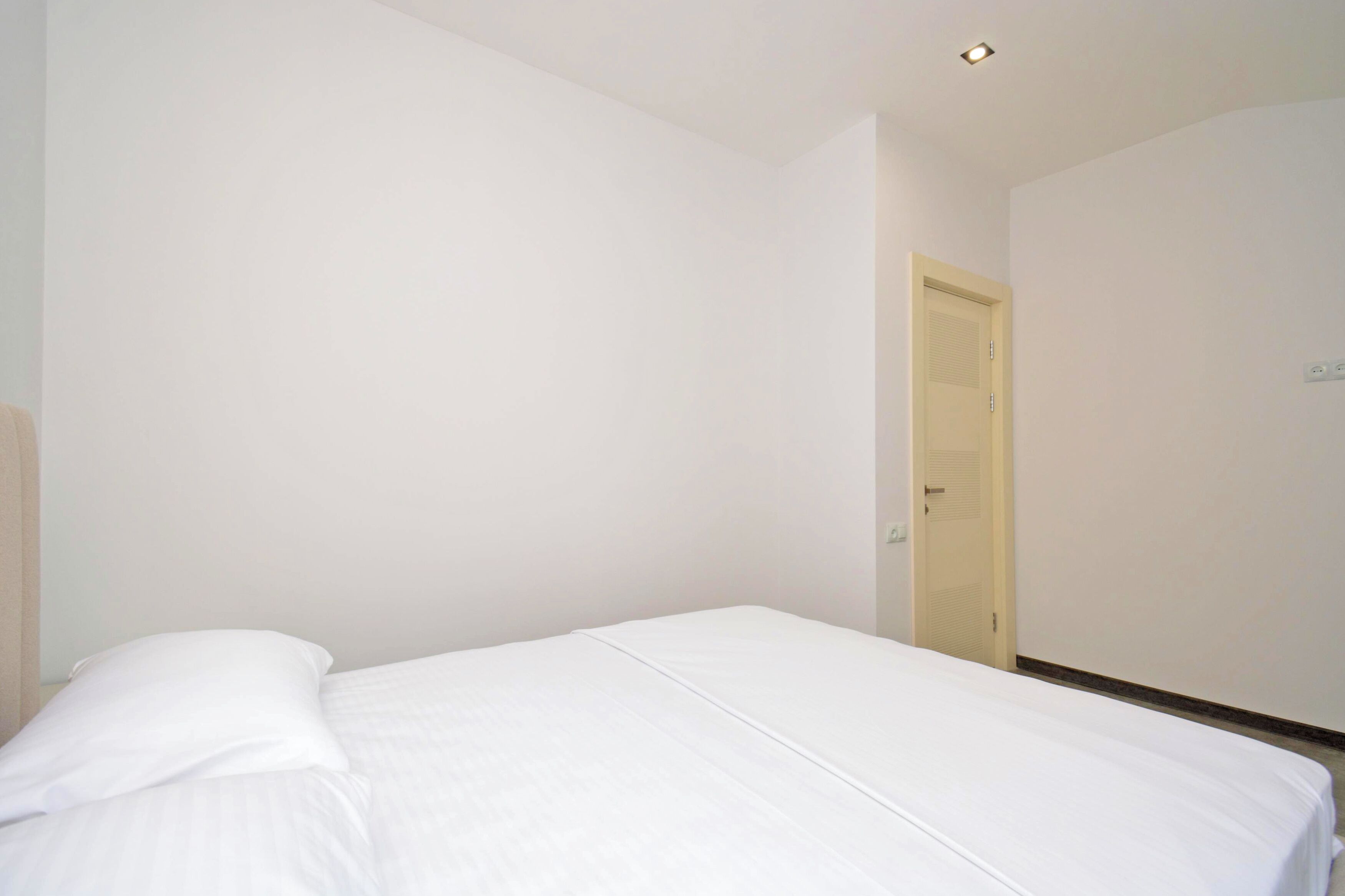 A room with a bed, a door, and a light fixture.