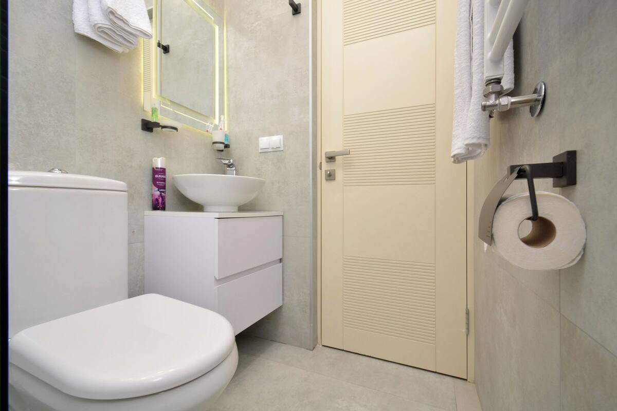 A modern bathroom with a toilet, sink, and mirror.