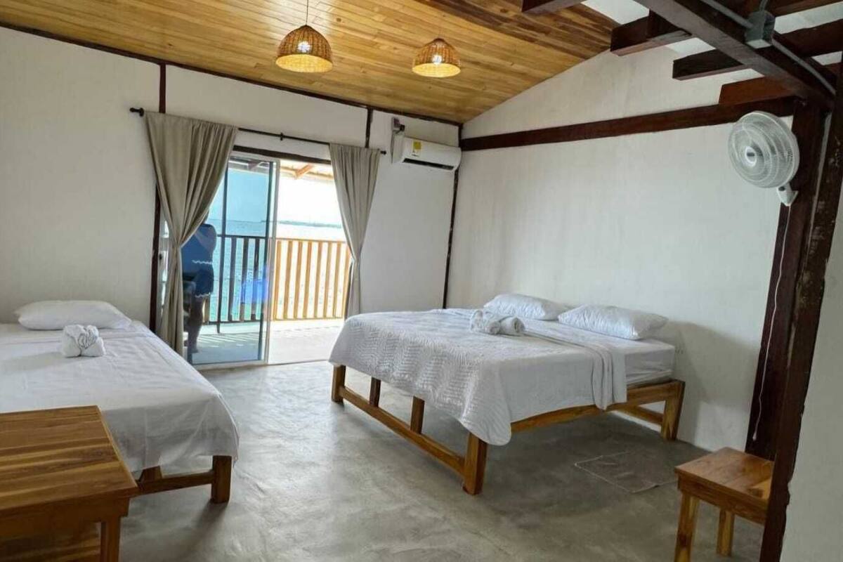 A room with two wooden beds, a ceiling fan, and a view through a glass door.