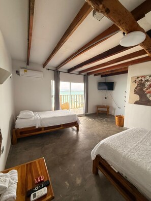 A bedroom with two beds, a television, and a balcony with a view. - w cabañas beach (Cartagena)
