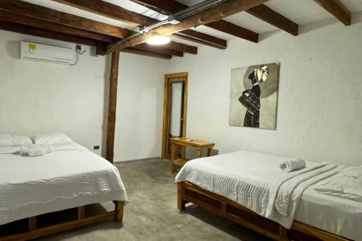 A bedroom with two single beds, a wooden bench, a mirror, and a painting on the wall.
