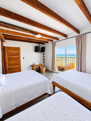 A hotel room with two beds, a TV, a wooden ceiling, a balcony with a view of the sea, and a wicker chair. - w cabañas beach (Cartagena)