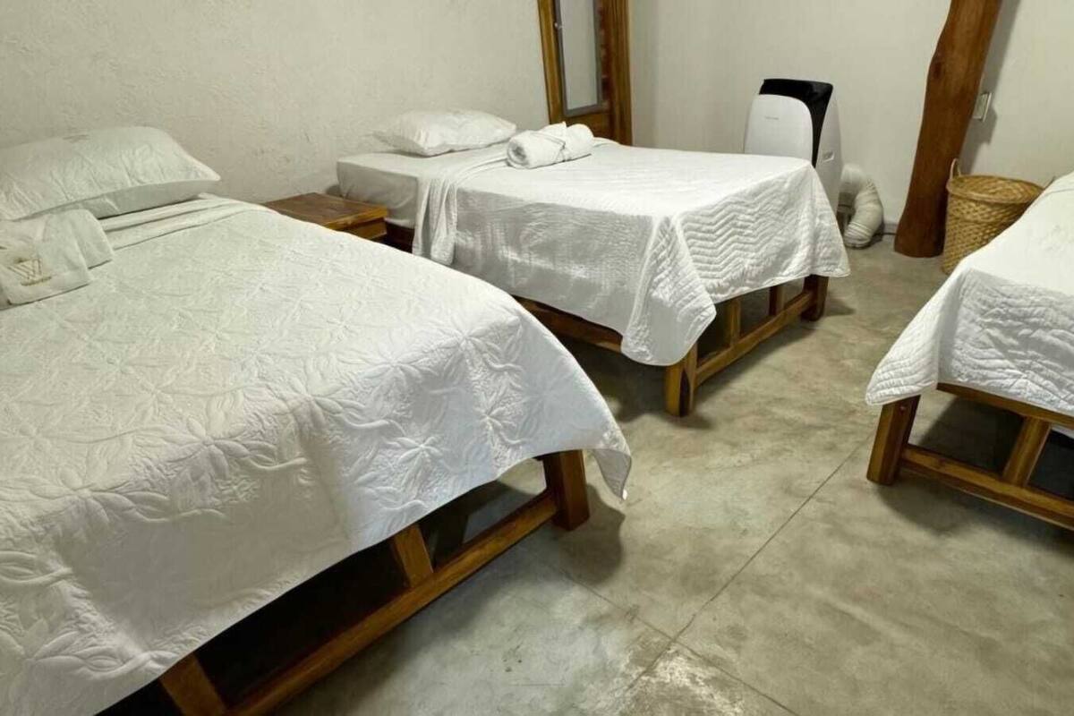 A room with three wooden beds, each with white bedding and pillows.