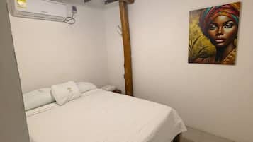 Quarto com cama, ar condicionado e um quadro na parede.