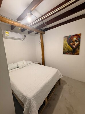 A bedroom with a bed, an air conditioning unit, and a painting on the wall. - w cabañas beach (Cartagena)