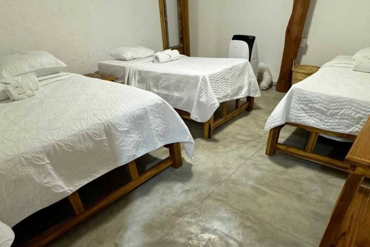 A room with three wooden beds, each with white linens and pillows.