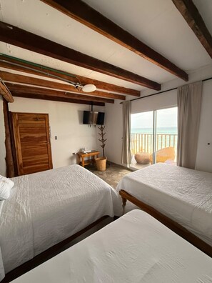 A room with two beds, wooden beams, a television, a window with a view, and a door. - w cabañas beach (Cartagena)