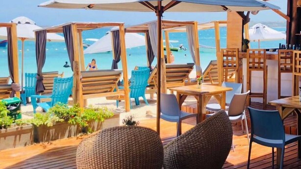 A beachside restaurant with wooden furniture, outdoor seating, and a view of the sea. - w cabañas beach (Cartagena)