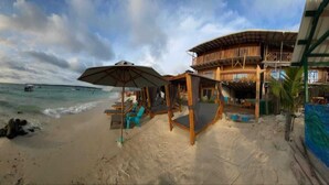 A beach with a wooden structure, umbrellas, and lounge chairs. - w cabañas beach (Cartagena)