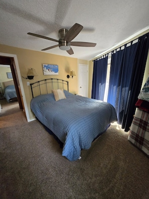 A bedroom with a bed, a ceiling fan, a door, and a window with curtains. - Updated 2-bedroom condo in Angel Fire 1 BLOCK FROM LIFTS (Angel Fire)